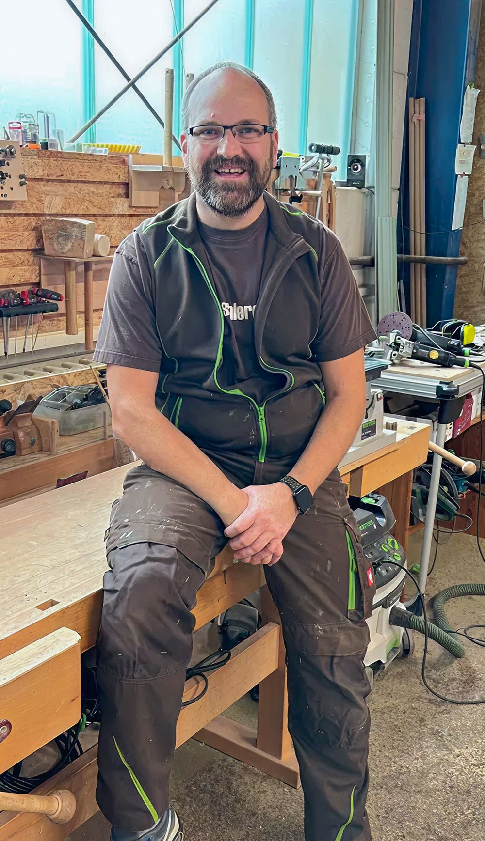 Sven Gudrian sitzt auf einem Holztisch und lächelt